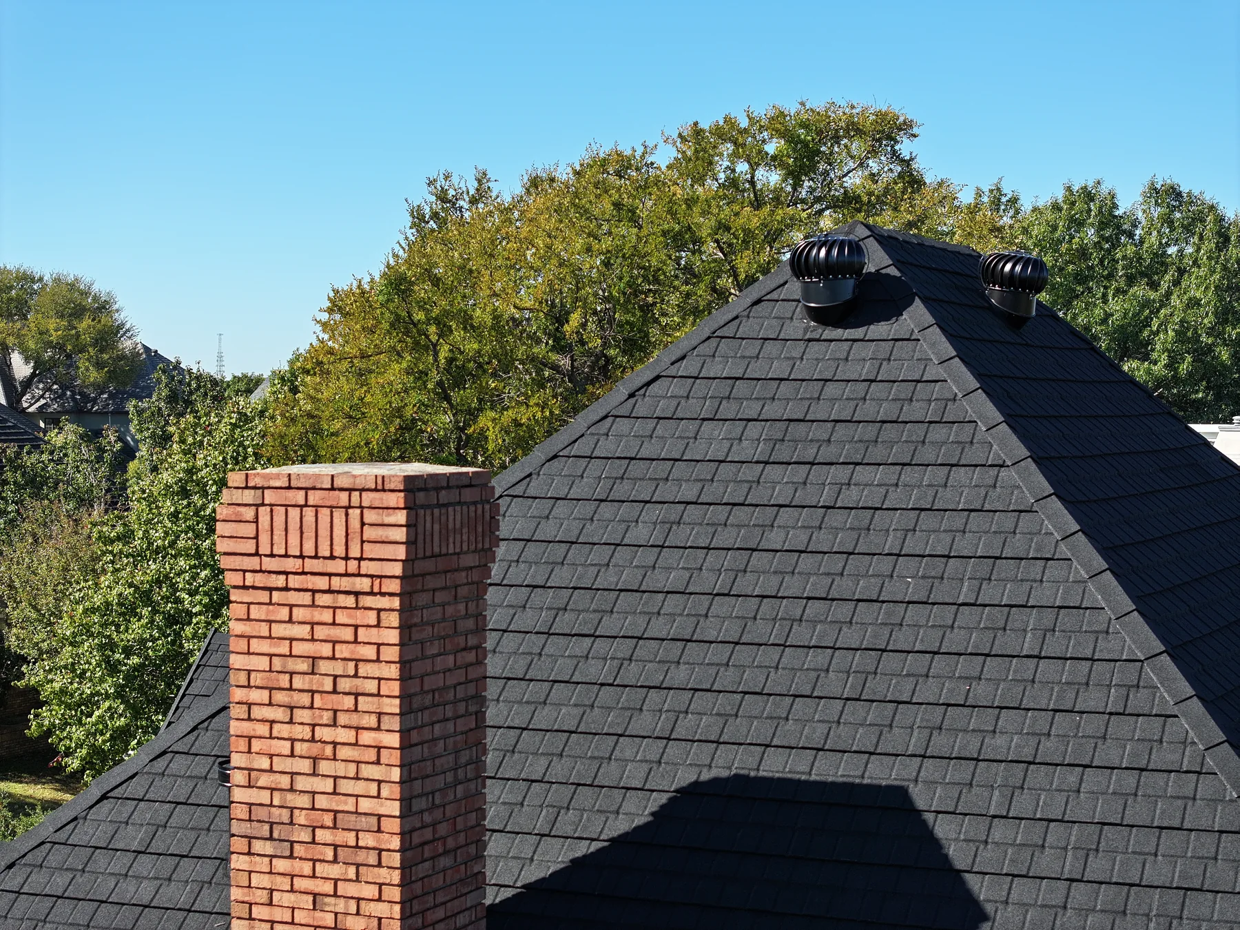 Black Stormetal shingles around a brick chimney and roof ridge